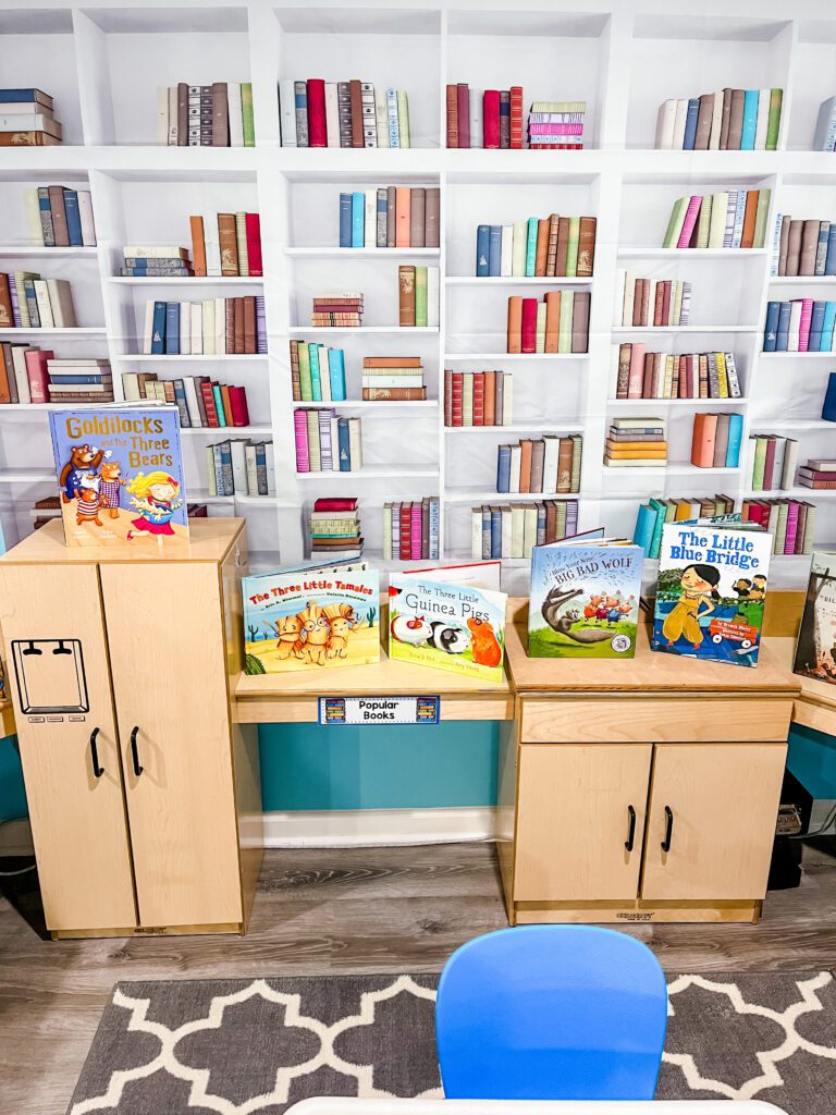 Preschool library dramatic play center - book shelf backdrop with books lining a counter