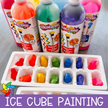 Ice cube tray filled with colorful plastic penguins frozen into paint, displayed in front of bottles of bright BioColor paint with a label reading “Ice Cube Painting.”