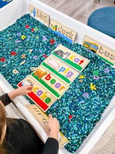 Preschool classroom student puts together a wooden word puzzle.