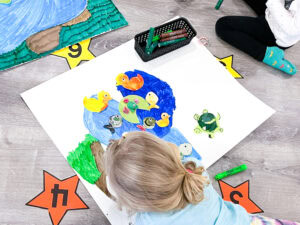 Preschool child adding a new detail to their pond mural as part of a multi-day art project.