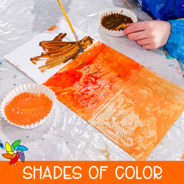 Preschool child painting orange color swatches on folded paper during a color mixing art activity.