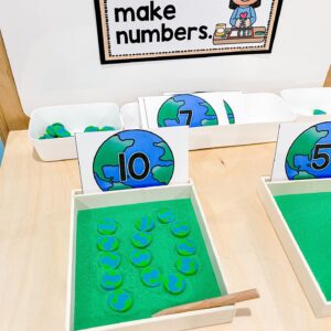 Counting tray with green sand, a “10” earth-themed number card, and ten earth counters arranged inside the tray.