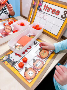 Students use mini pumpkin counters and number mats for a hands-on counting activity at the preschool math center.