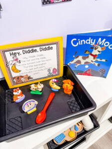 Hey Diddle Diddle retelling tray with rhyme card, figurines, a red spoon, and the book Cindy Moo.