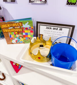 Jack and Jill preschool nursery rhyme retelling tray with a plastic crown, blue pail, printed rhyme card, and a related storybook.