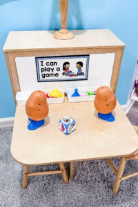 Preschool math center with Potato Head toys, plastic parts, and a foam dice for roll-and-build game.