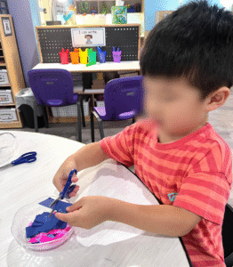 Preschool child practicing scissor skills during a play-based learning activity