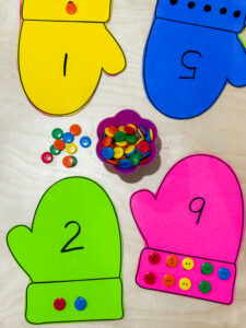 Colorful mitten-shaped number cards paired with matching buttons for a preschool counting activity.