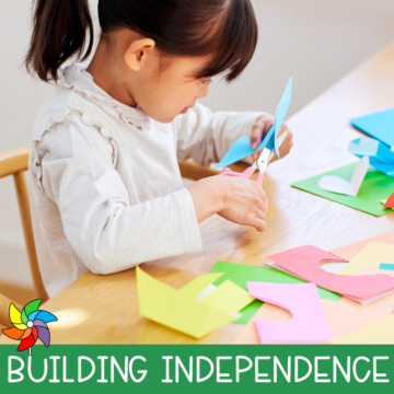 Preschool child cutting paper with scissors during an independent fine motor activity at a classroom table.
